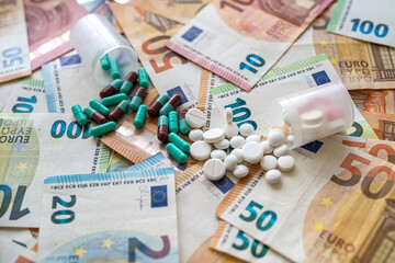 different medicine pills or capsules over euro bills