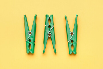 Three green clothespins on color background