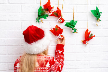 Child girl opening small gifts surprises advent calendar hanging on the wall. Happy waiting...