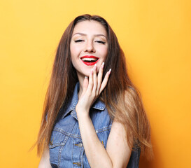 Lifestyle, emotion and people concept: Young fashion model posing in studio over yellow background