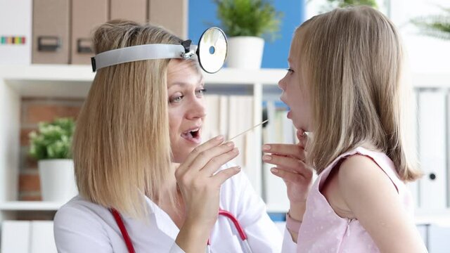 ENT woman conducts physical examination of little girl throat in clinic 4k movie