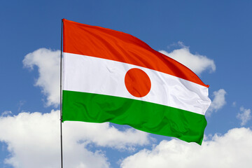 Niger flag isolated on the blue sky background. close up waving flag of Niger. flag symbols of Niger. Concept of Niger.