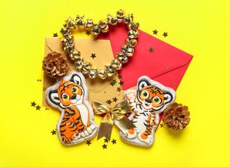 Beautiful Christmas composition with tasty cookies in shape of tigers, envelopes and bells on yellow background