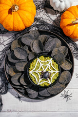 Spooky Halloween black potato chips with guacamole dip