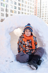Cute boy playing in the snow castle igloo