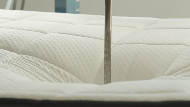 Mattress being tested with hydraulic press in mattress production facility - close