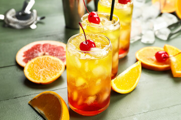 Glasses of tasty Tequila Sunrise cocktail on green wooden background