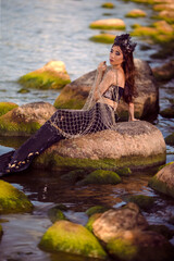 Sensual Mermaid With Net At Rocky Sea Coast Wearing Seashell Decorated Crown and Black Shiny Tail On Slim Body Covered With Strasses Posing As Mistress Queen of Sea.
