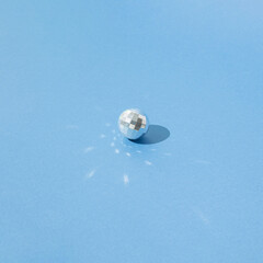 Glittering New Year Christmas disco ball in silver color on a blue pastel background. Copy space.