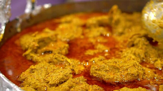 Cinematic view of Traditional bengali chicken rezala in white curry sauce with chili peppers close-up in a pan on the table. horizontal