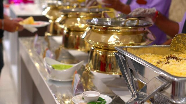 Waiter serving biryani with meat dish on some festive Indian event, party or wedding reception.