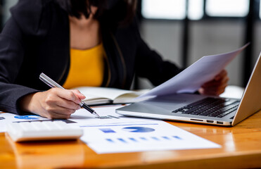 A Businesswoman hand using a calculator with documents financial statistic stock photo,discussion...