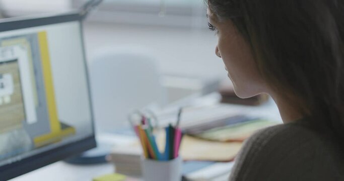 Creative interior designer sitting at desk and working on a project on her computer
