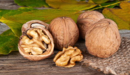 fresh kernels, broken and whole walnuts close-up on wooden background with yellow fall leafs