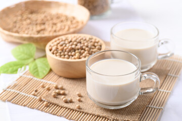 Soy milk in a cup glass and soy beans in a bowl on white background, Healthy drink