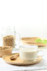Soy milk in a cup glass with spoon on wooden plate with white background, Healthy drink