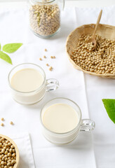 Soy milk in a cup glass and soy beans in a bamboo basket and bowl on white background, Healthy drink