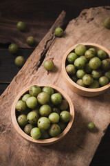 Wild Indian gooseberry or amla in a bowl on wooden background, Fruit tree in Asia use in various cuisine, herbal medicine and rich vitamin C