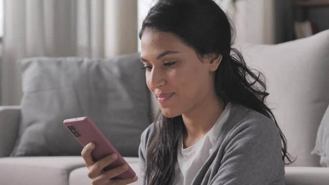 side view portrait of young brunette latina woman using smart phone mobile at home,hispanic smiling female holding smartphone browsing internet online indoors
