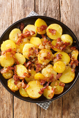 Bratkartoffeln German Cottage Potatoes With Bacon and Onion close up in the plate on the table. Vertical top view from above