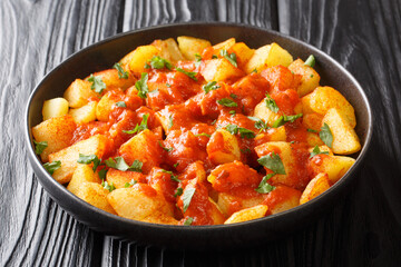 Patatas bravas or potatoes in bravas sauce are a classic Spanish tapas dish close up in the plate on the table. Horizontal