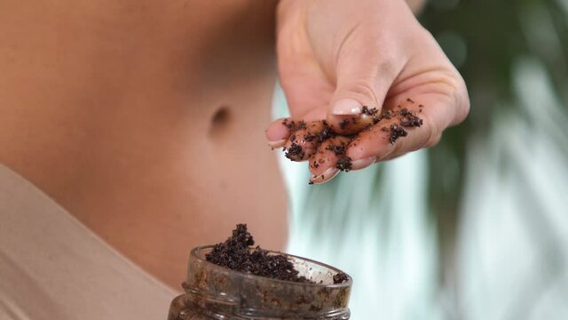 Woman beige underwear holds jar belly level. Took coffee oil scrub high texture detail my fingers. Drives fingertips rubs hand tastes sensation. Cosmetics women body care skin toning scrub advertising