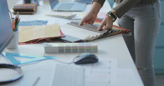 Professional dectorator choosing fabric swatches, she is touching the samples with her hands