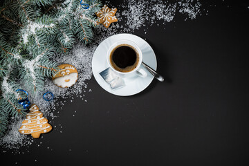 Christmas and New Year decoration composition. Top view of fur-tree branches on dark background with place for your text. Cups of fragrant coffee with marshmallows, gingerbread and chokolate.