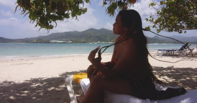 Latin Girl Sat in Shade on Tropical White Sandy Beach Gets Up to Swim in Ocean Water, Playa Teco Maimon