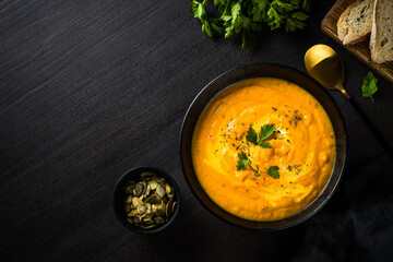 Pumpkin soup puree with cream. Top view image at black stone table.