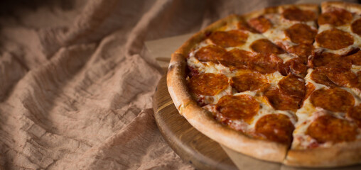 Delicious, aromatic, hot pepperoni pizza on a brown background. Baner