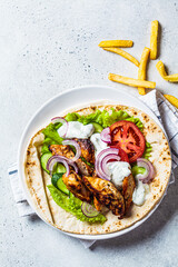 Cooking chicken gyros with vegetables, french fries and tzatziki sauce. Greek food concept.