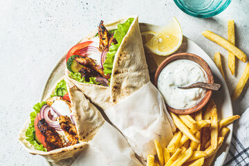Chicken gyros with vegetables, french fries and tzatziki sauce on plate. Greek food concept.