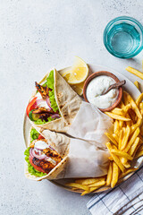 Chicken gyros with vegetables, french fries and tzatziki sauce on plate. Greek food concept.