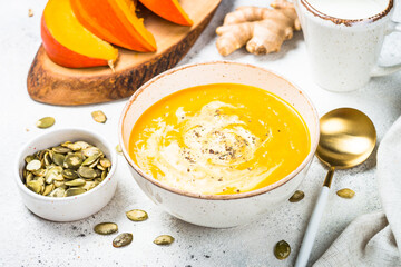 Pumpkin and carrot soup puree with cream and ginger in the craft bowl. Close up.
