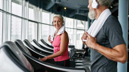 Elderly couple working out on treadmill in fitness center