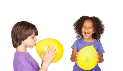 Two happy children blowing up yellow balloons