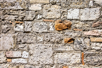 Stone antique old wall as a background or texture. Vintage background of a fortress wall in loft and grunge style with place for text and copy space.