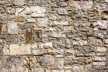 Stone antique old wall as a background or texture. Vintage background of a fortress wall in loft and grunge style with place for text and copy space.
