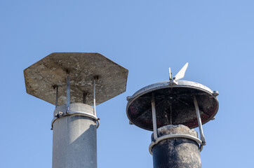Smoke pipes with canopies against the blue sky. Two asbestos-cem