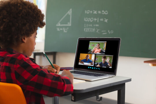 African american boy using laptop for video call, with diverse elementary school pupils on screen