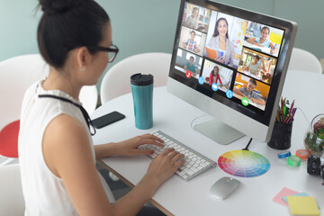 Asian girl holding computer for video call, with smiling diverse elementary school pupils on screen