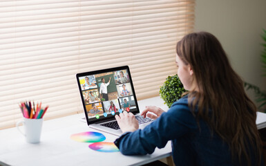 Caucasian girl using laptop for video call, with smiling diverse elementary school pupils on screen