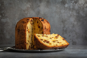 Panettone, italian type of sweet bread with raisins originally from Milan, Christmas and New Year food. Gray background. - obrazy, fototapety, plakaty