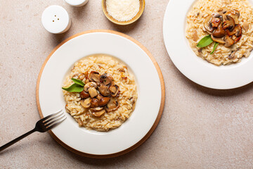 Risotto with mix of mushroom and taleggio cheese on stone beige table. Italian dinner. Two...