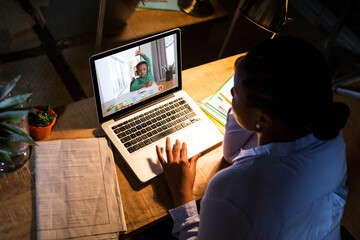 Fototapeta na wymiar African american woman using laptop for video call, with elementary school pupil on screen
