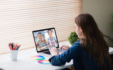 Fototapeta na wymiar Caucasian girl using laptop for video call, with smiling diverse high school pupils on screen