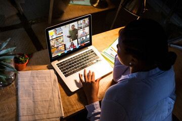 Fototapeta premium African american woman using laptop for video call, with diverse elementary school pupils on screen