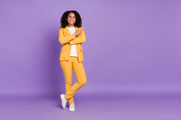 Photo of good mood cute lady wear yellow suit glasses smiling pointing empty space isolated purple color background