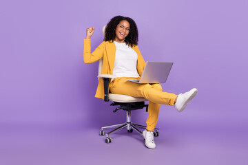 Photo of excited lucky woman dressed yellow suit spectacles sitting chair writing device rising...